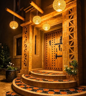 Une entrée en bois, avec un escalier menant à une porte, le tout entouré d’un sol carrelé orné d’un motif géométrique.