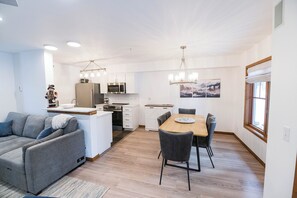 Une cuisine moderne avec des meubles blancs, un four à micro-ondes et un coin repas comprenant une table et des chaises en bois.