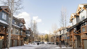 Une rue enneigée bordée d’immeubles à plusieurs étages, dotés de balcons en bois et de façades en pierre.