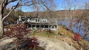 A house with a large porch, a driveway, and a lake in the background.