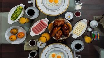 Et morgenbord med tallerkener med æg, bagværk og frugt.