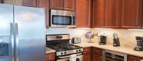 A kitchen with wooden cabinets, stainless steel appliances including a refrigerator, microwave, stove, and oven, a coffee maker, and a dishwasher.