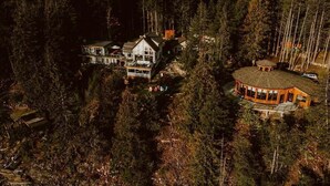 A large, multi-story house surrounded by dense forest. - The Sentinel (Kaslo)