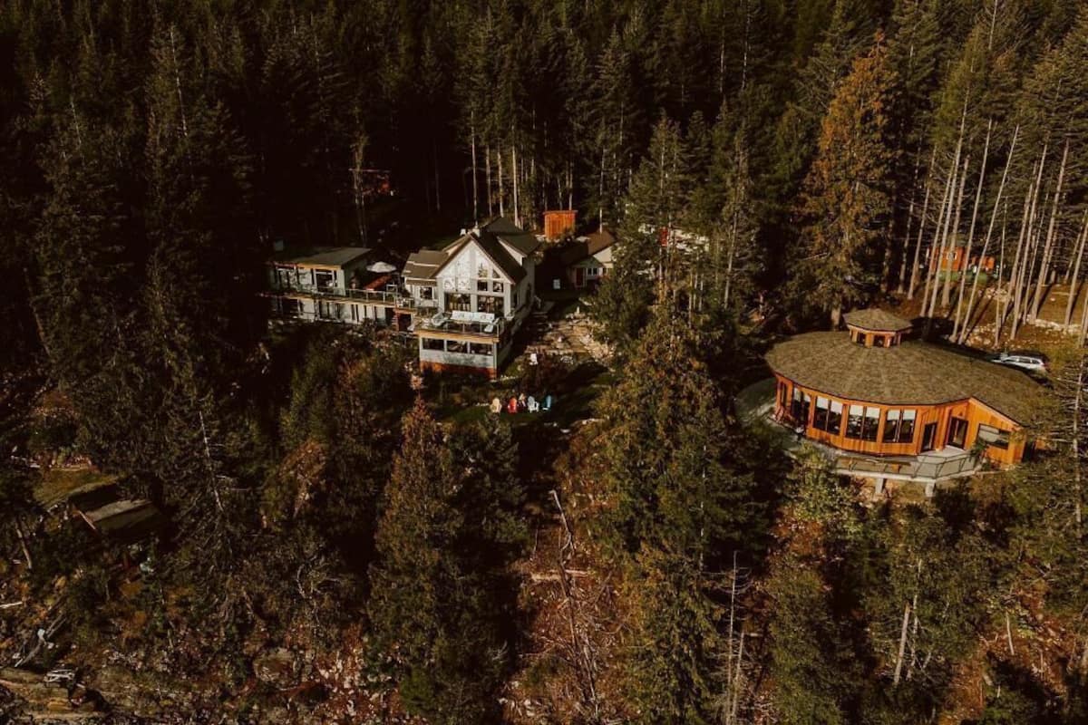 Una casa grande de varios pisos rodeada de un bosque denso.