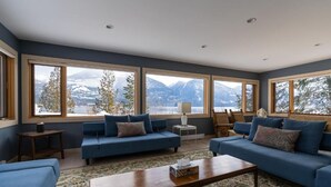 A spacious living room with large windows offering a mountain view. - The Sentinel (Kaslo)