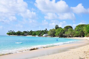 A beach with clear turquoise water, a boat, and a sandy shore.