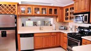 A kitchen with wooden cabinets, stainless steel appliances, and a tiled backsplash. - ZenBreak - Seagaze Villa (Gibbes)