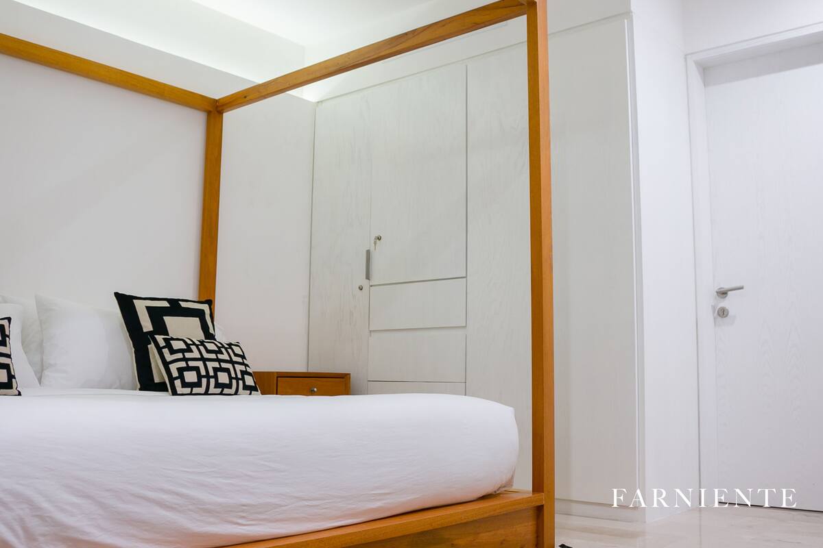 A bedroom with a four-poster bed, a wooden nightstand, and a white wardrobe.