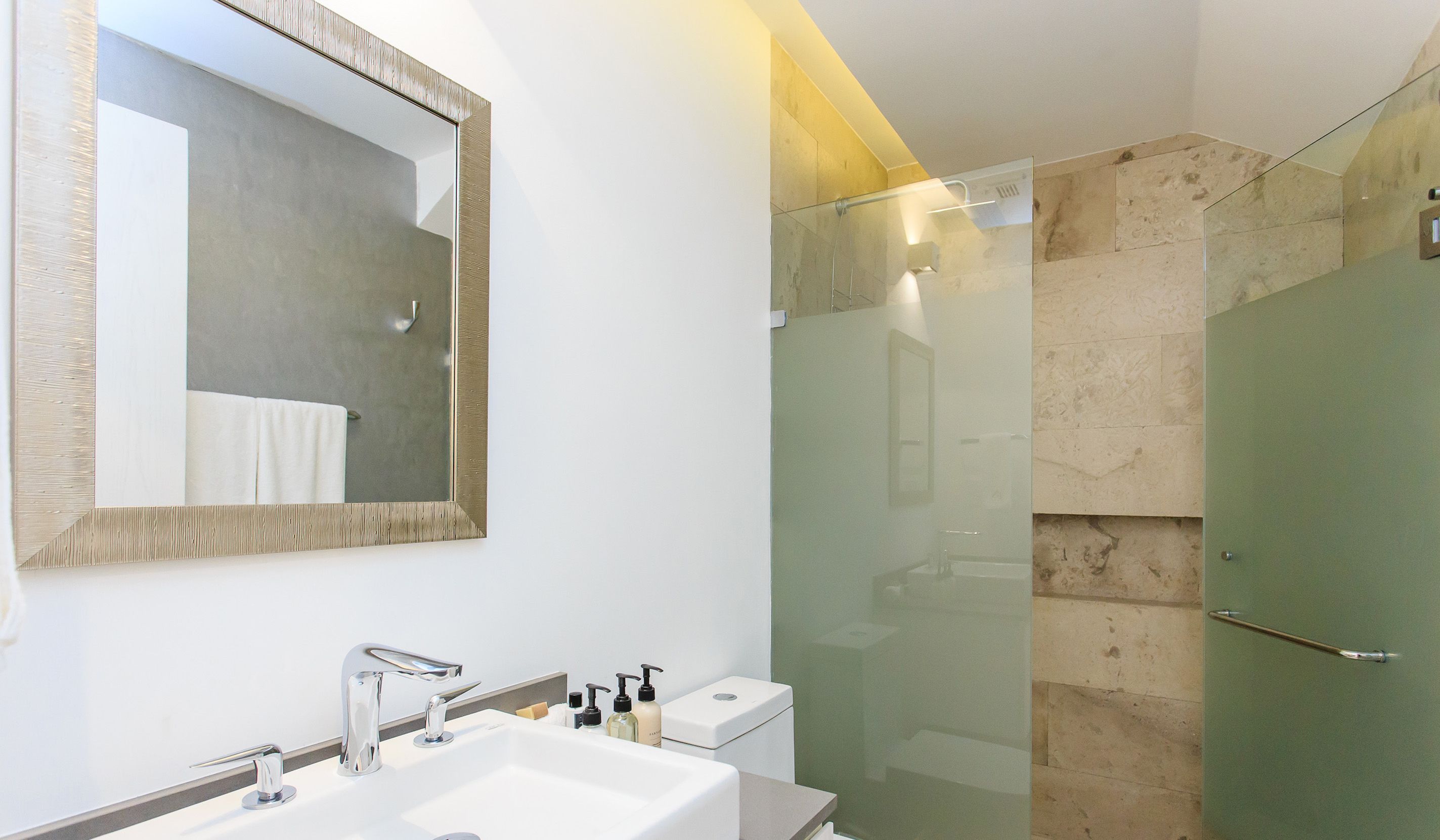 A modern bathroom with a large mirror, a sink, and a glass-enclosed shower.