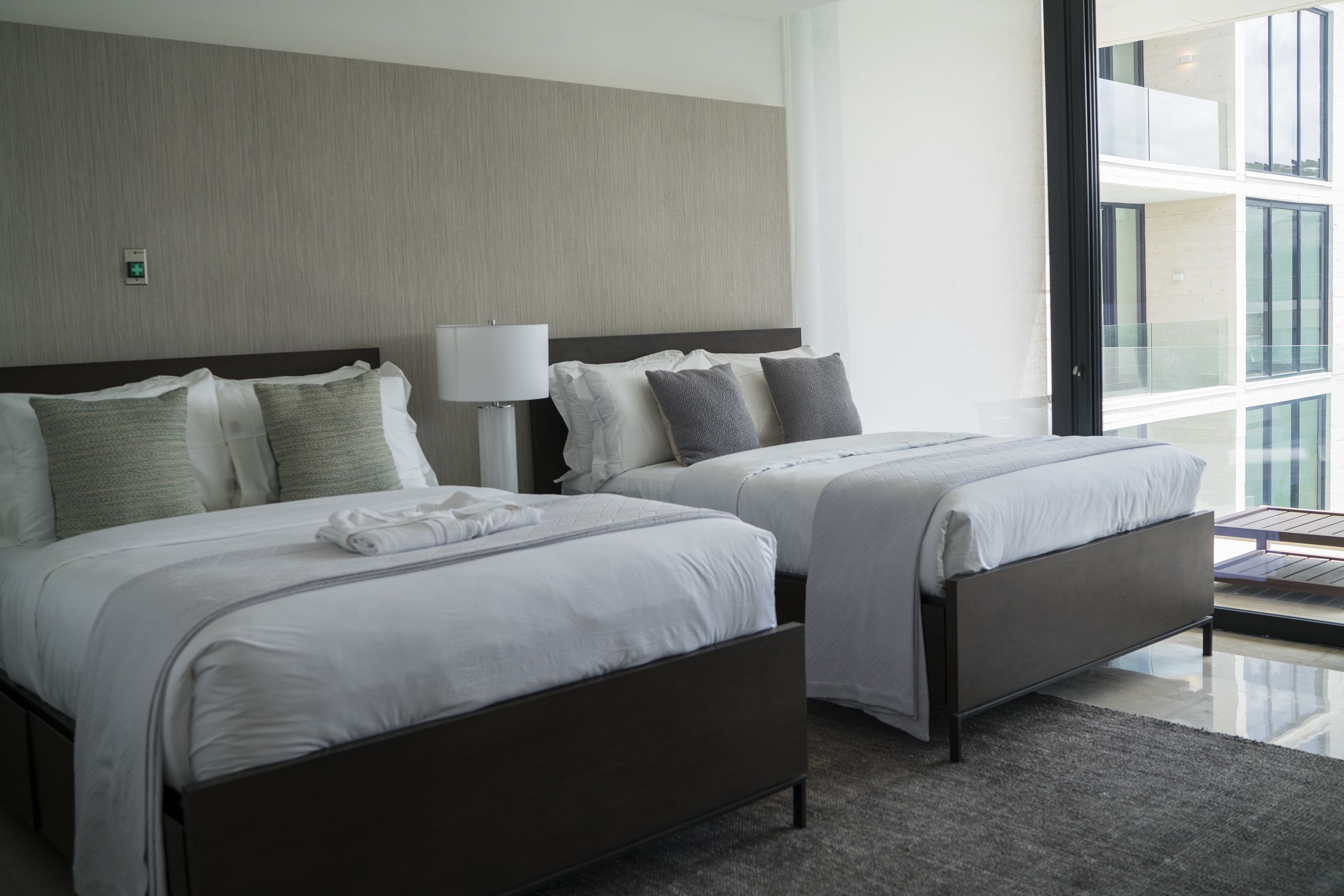 A hotel room with two beds, a large window, and a modern design.