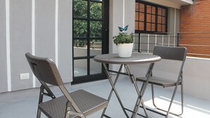 A balcony with two chairs, a small round table, and a potted plant. - Hotel Poma - Rosa (Medellín)