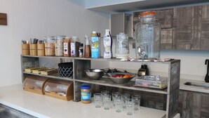 A kitchen with shelves holding various food items, a blender, and a sink. - Hotel Poma - Rosa (Medellín)