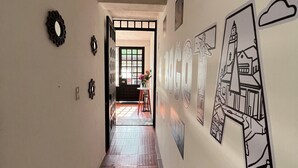 Un pasillo con suelo de baldosas, ventilador de techo y adornos en las paredes, incluyendo cuadros enmarcados y un espejo.