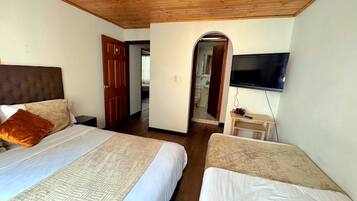 A hotel room with two beds, a wooden ceiling, a TV, and a small table with a camera.