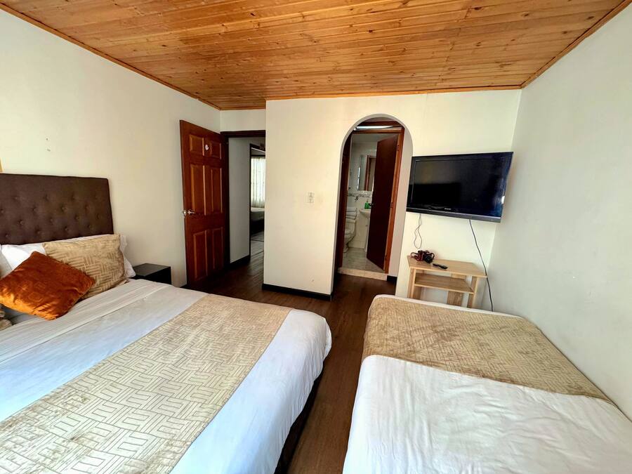 A hotel room with two beds, a wooden ceiling, a TV, and a small table with a camera.