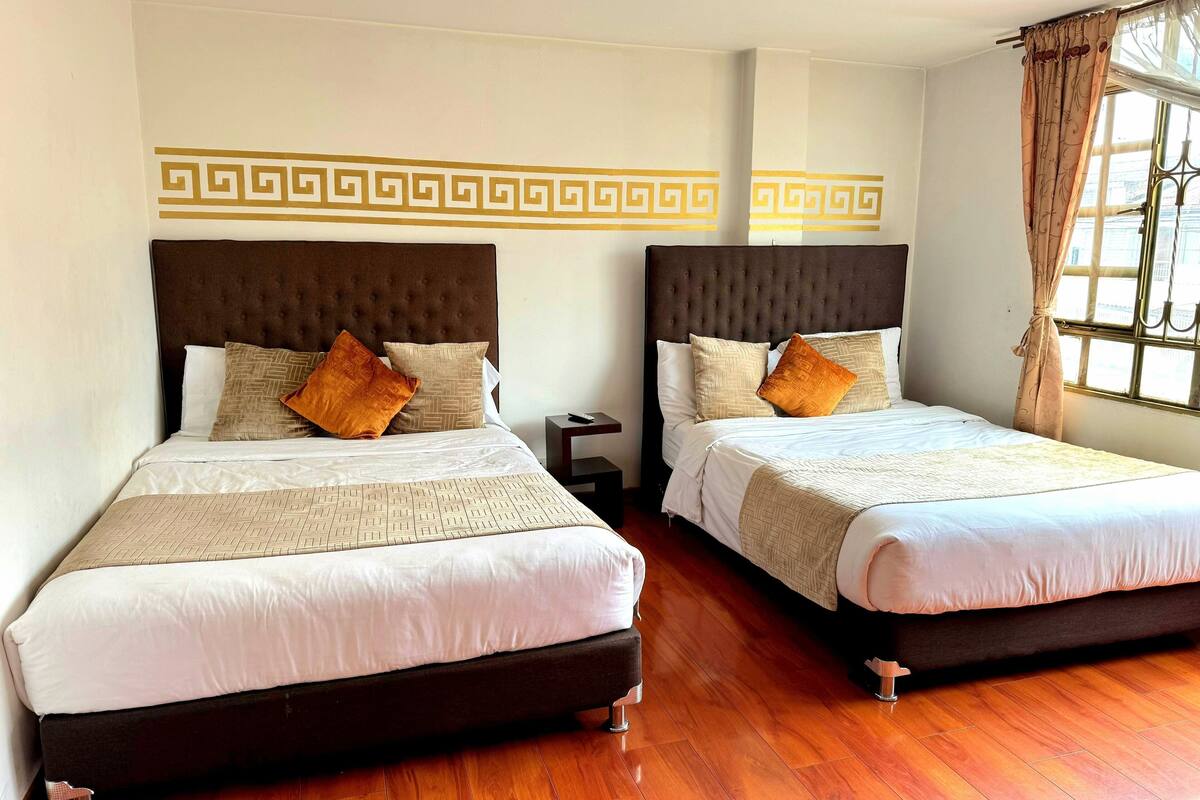 Two double beds with headboards, a wooden floor, and a decorative wall pattern.