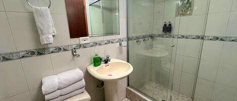 A bathroom with a toilet, sink, and glass-enclosed shower.