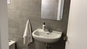 A bathroom with a white sink, a mirror, and a towel hanging on the wall.