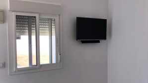 A room with a window, an air conditioning unit, and a mounted television.