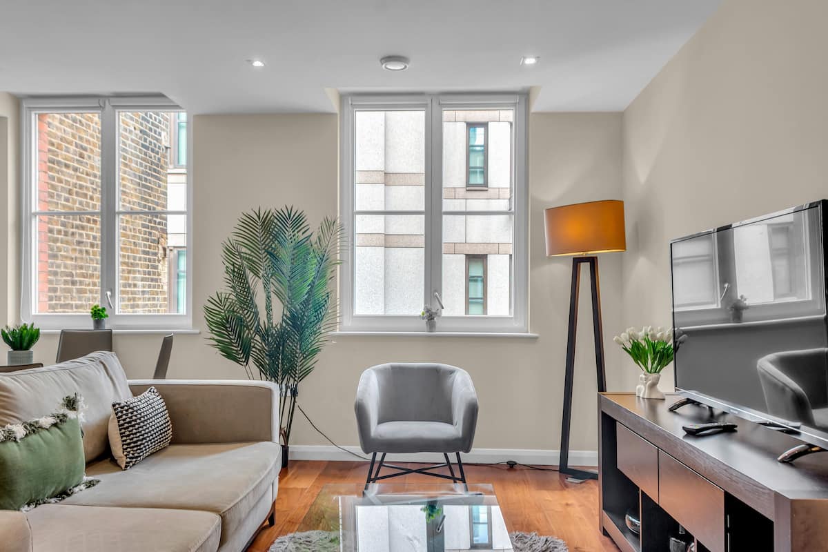 A modern living room with a sofa, armchair, TV, and a lamp.