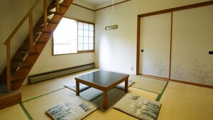 Una habitación japonesa tradicional con suelo de tatami, una mesa de madera baja, una puerta corredera y una ventana con diseño de cuadrícula.