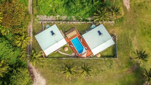An aerial view of a property with two separate buildings, each with a swimming pool and a covered patio area. - Cook Islands Holiday Villas Turangi (Rarotonga)