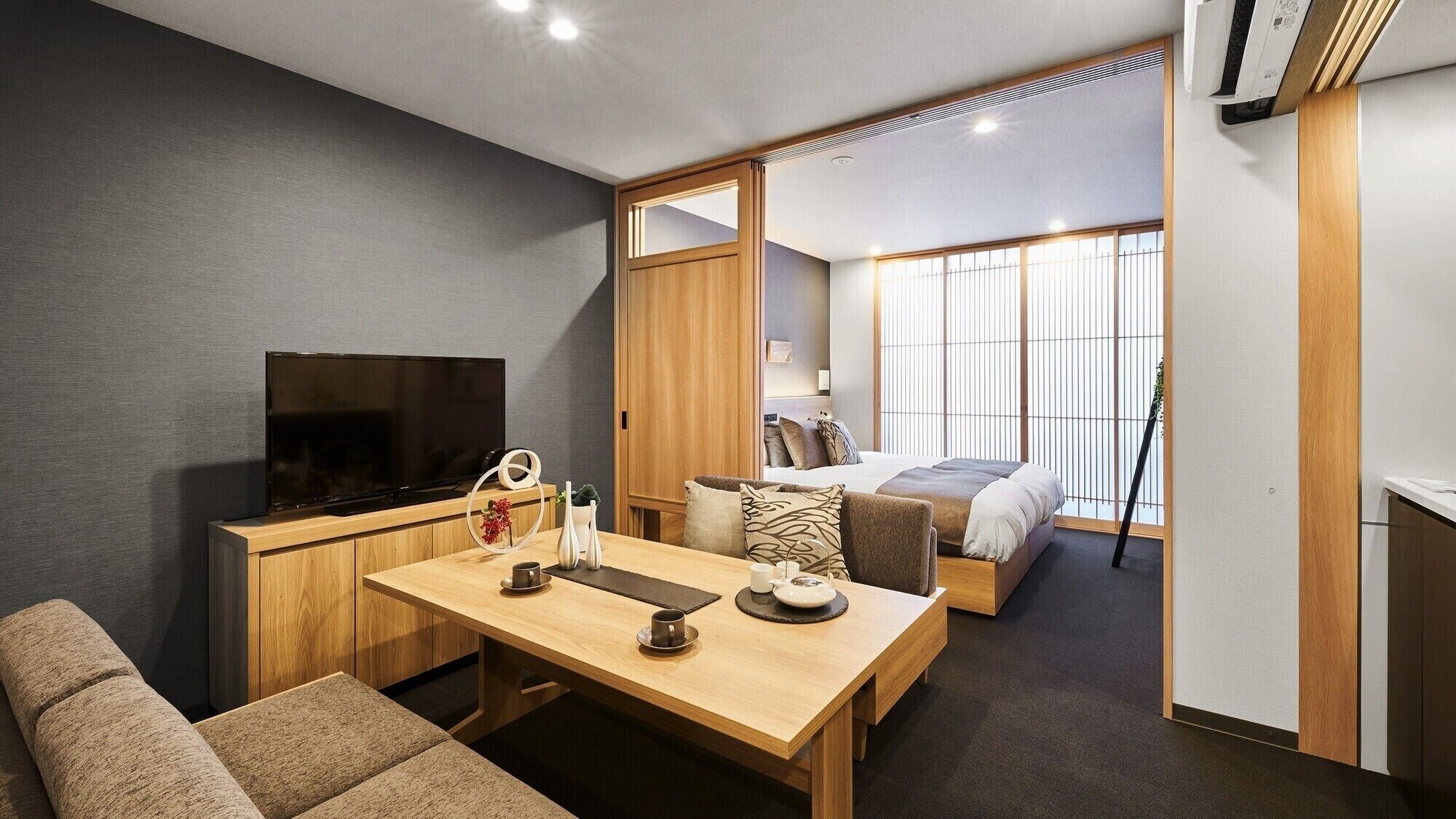 Una habitación de hotel moderna con televisión, muebles de madera, una cama y vistas a la ciudad.