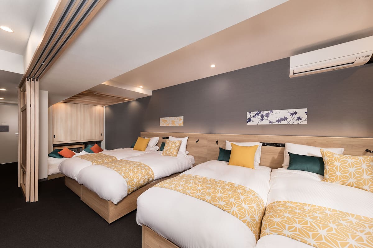 A hotel room with two beds, a wooden headboard, an air conditioning unit, and a wall-mounted artwork.