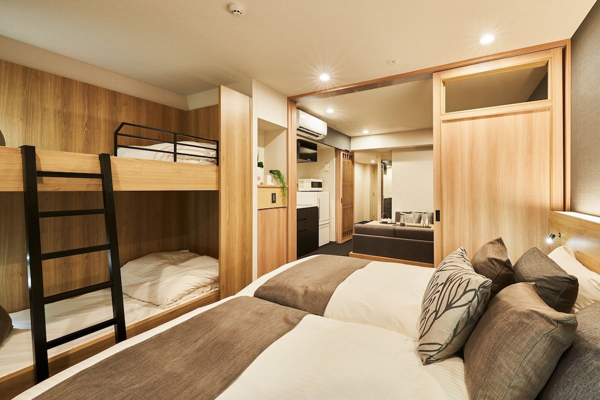A compact hotel room with a bunk bed, a desk, and a kitchenette.