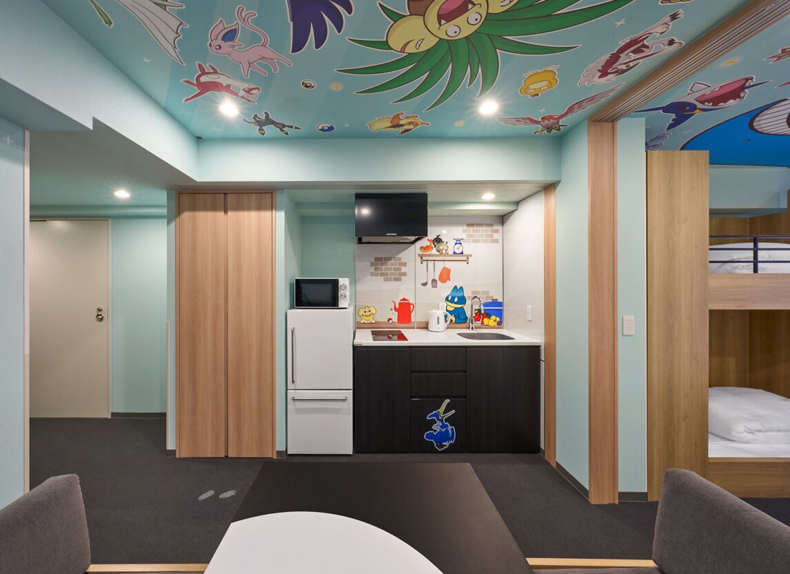 Une chambre avec un coin cuisine, un lit superposé et une fresque peinte au plafond.