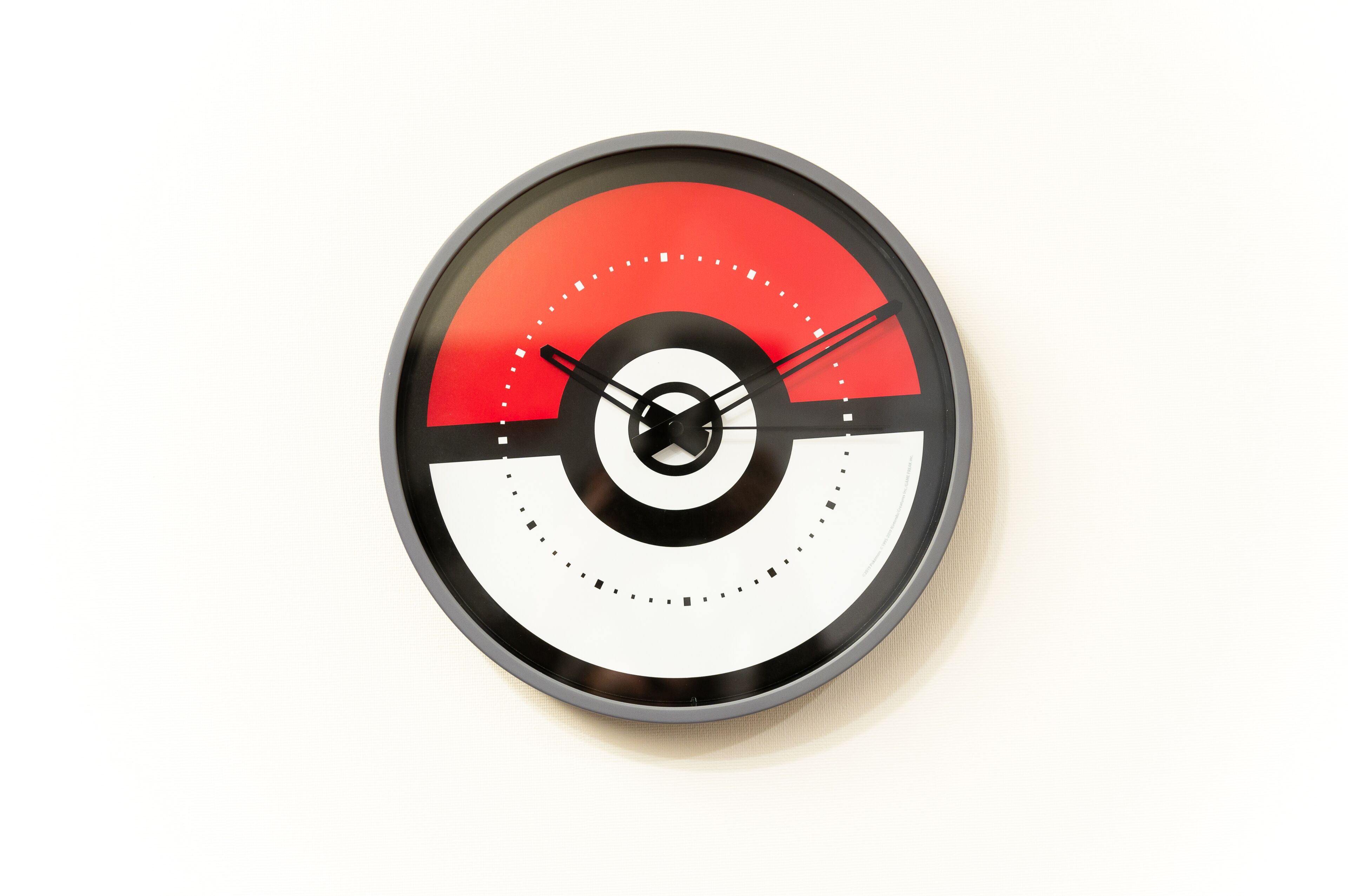 Un reloj circular con esfera roja y blanca, agujas negras y centro negro.