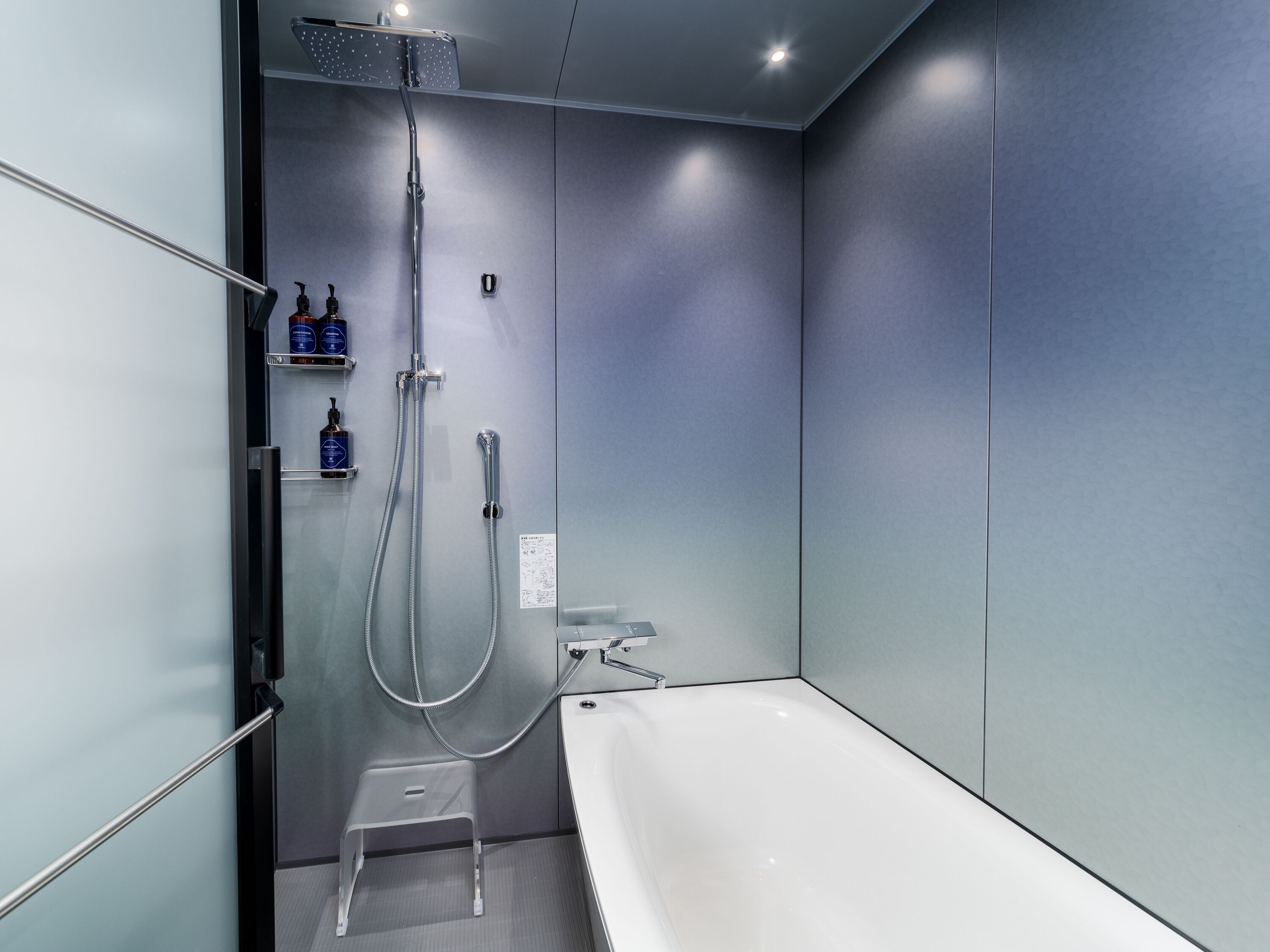 A modern bathroom with a walk-in shower, a bathtub, and a small step stool.