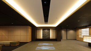 Un moderno vestíbulo de hotel con una zona de estar central, una recepción y un muro con diseño.