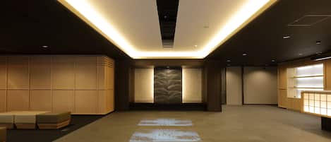 Um hall de hotel moderno com área de estar central, balcão de recepção e parede estampada.