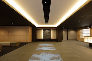 A modern hotel lobby with a central seating area, a reception desk, and a patterned wall.