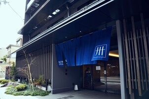 A modern building with a blue awning displaying a white logo.
