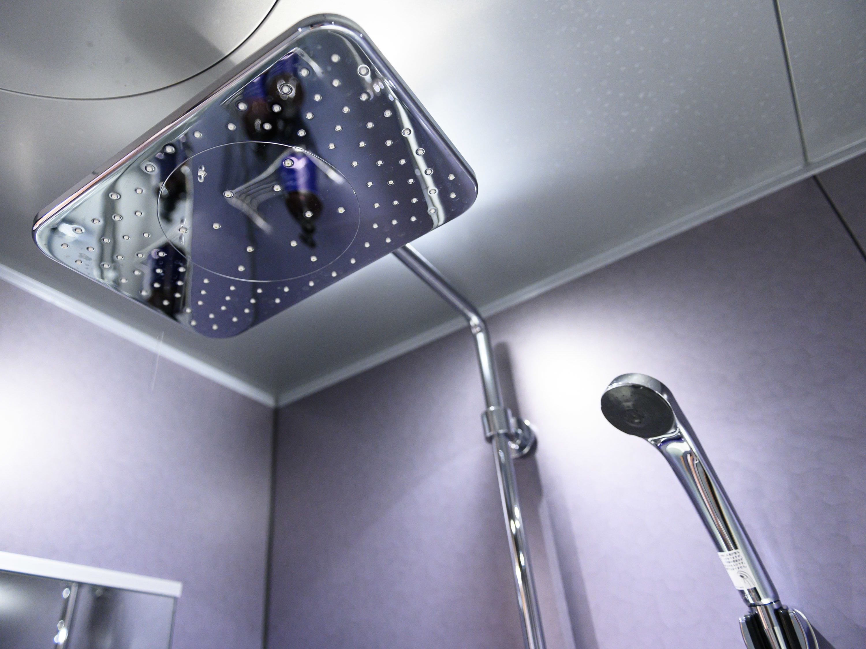 A shower with a handheld attachment and a wall-mounted showerhead.