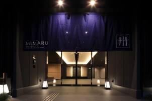 The entrance of Mimaru Apartment Hotel with a modern design, featuring a dark facade, illuminated entrance, and a clear signboard.