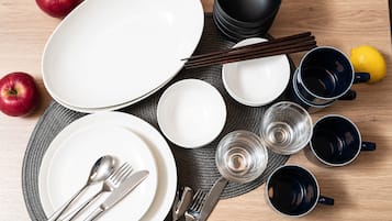 A neatly arranged dining table with plates, cutlery, chopsticks, and a lemon.