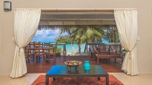 A room with a view of the ocean, a dining table, chairs, and a small table with a bowl and vase. - Cook Islands Holiday Villas Muri (Rarotonga)