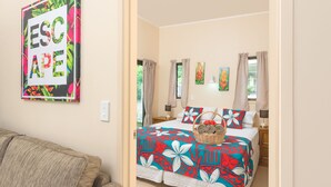 Ein Schlafzimmer mit floralem Bettüberwurf, einem Korbwäschesammler mit Handtüchern und zwei Bildern an der Wand.