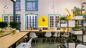 A modern interior with a long wooden table, multiple chairs, and a variety of potted plants. - Little Pig Home - Hostel (Da Nang)