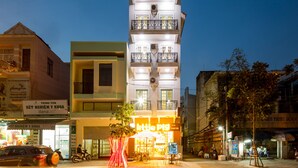 A multi-story building with a brightly lit ground floor featuring a cafe named "Little Pig Tea Coffee". - Little Pig Home - Hostel (Da Nang)
