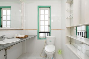 A bathroom with a white sink, a toilet, and a window with a green frame.