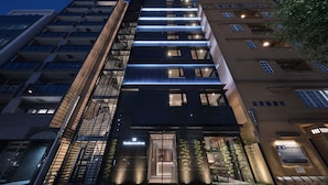 A modern hotel building with a prominent entrance, multiple floors, and illuminated windows.