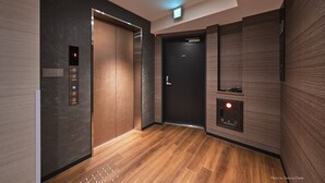 An elevator with a digital display and buttons, a door with a lock, and a floor with a patterned design.