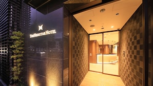 The Hedistar Hotel entrance with a glass facade, checkered wall pattern, and a reception area visible inside.