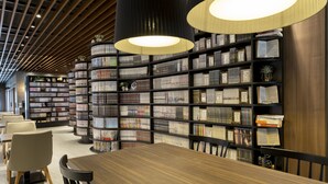 A modern library with bookshelves, a wooden table, and chairs.