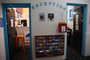 A reception area with a bulletin board displaying various notices and a collection of magazines. - Hump Backpackers (Potts Point)