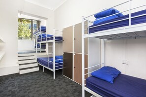 A dormitory room with bunk beds, a window with a view, and a carpeted floor. - Hump Backpackers (Potts Point)